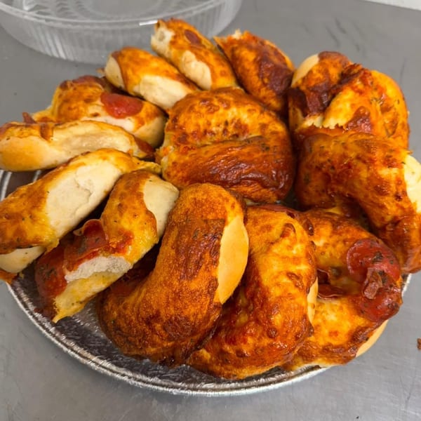 A platter of Fancy Bagels' pizza bagels, some whole and some cut in half, with pepperoni and cheese.