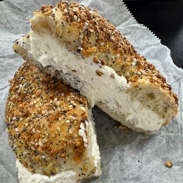An everything bagel from Fancy Bagels, sliced in half with a thick layer of cream cheese.